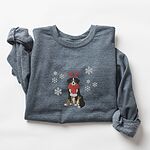 Dark Heather crewneck sweatshirt laid flat with rolled sleeves, embroidered with a sitting tricolor Bernese mountain dog in red reindeer antlers and a red knit scarf, framed by snowflakes