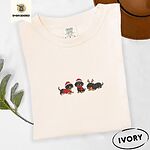 Ivory Comfort Colors T-shirt embroidered with three black and tan dachshunds in Santa hats, a red sweater, a red scarf and reindeer antlers