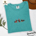 Seafoam Comfort Colors T-shirt embroidered with three black and tan dachshunds in Santa hats, a red sweater, a red scarf and reindeer antlers