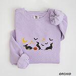 Orchid crewneck sweatshirt laid flat on white, embroidered with three black and tan dachshunds playing under a yellow crescent moon, gold stars and flying bats beside a small jack-o'-lantern
