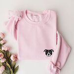 Light Pink crewneck sweatshirt laid flat with pink roses, embroidered with a small minimalist black and white pit bull face with a white blaze and grey ears on the left chest