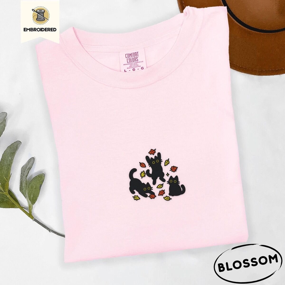 Black Cat Fall Shirt – Blossom Blossom Comfort Colors T-shirt embroidered with three black cats pouncing, leaping and sitting among falling red, orange and yellow autumn leaves