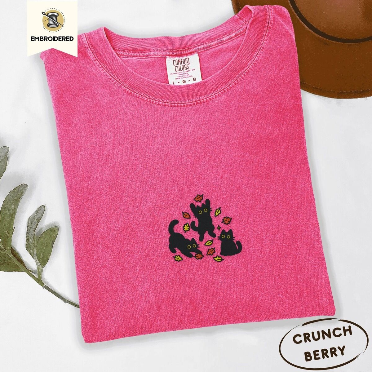 Black Cat Fall Shirt – Crunchberry Crunchberry Comfort Colors T-shirt embroidered with three black cats pouncing, leaping and sitting among falling red, orange and yellow autumn leaves