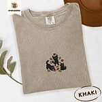 Khaki Comfort Colors T-shirt embroidered with three black cats pouncing, leaping and sitting among falling red, orange and yellow autumn leaves