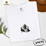 White Comfort Colors T-shirt embroidered with three black cats pouncing, leaping and sitting among falling red, orange and yellow autumn leaves
