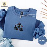 Indigo Blue crewneck sweatshirt folded with light jeans and dried twigs, embroidered with three black cats pouncing, leaping and sitting among falling red, orange and yellow autumn leaves
