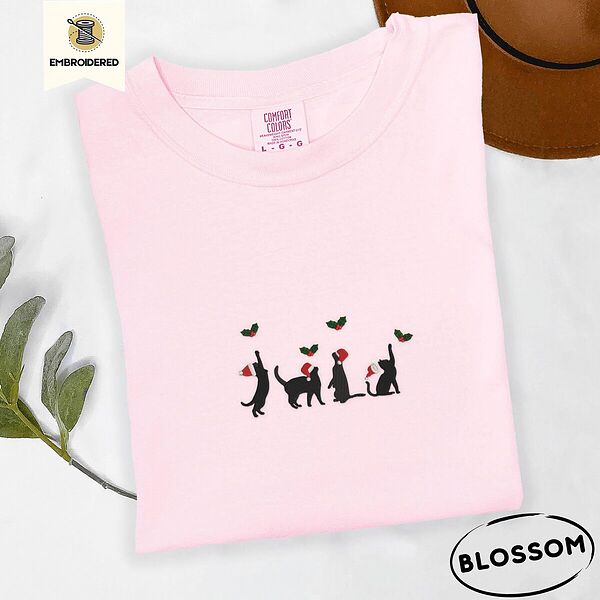 Blossom Comfort Colors T-shirt embroidered with four black cat silhouettes in Santa hats reaching for holly across the chest