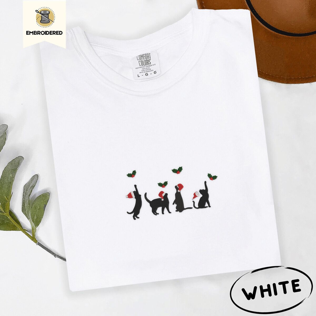 Black Cat Santa Hat Shirt – White White Comfort Colors T-shirt embroidered with four black cat silhouettes in Santa hats reaching for holly across the chest