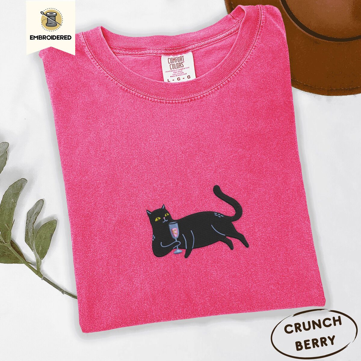 Black Cat Wine Shirt – Crunchberry Crunchberry Comfort Colors T-shirt embroidered with a black cat lounging on its side holding a stemmed glass of pink wine