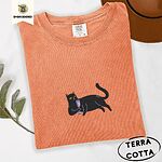 Terracotta Comfort Colors T-shirt embroidered with a black cat lounging on its side holding a stemmed glass of pink wine