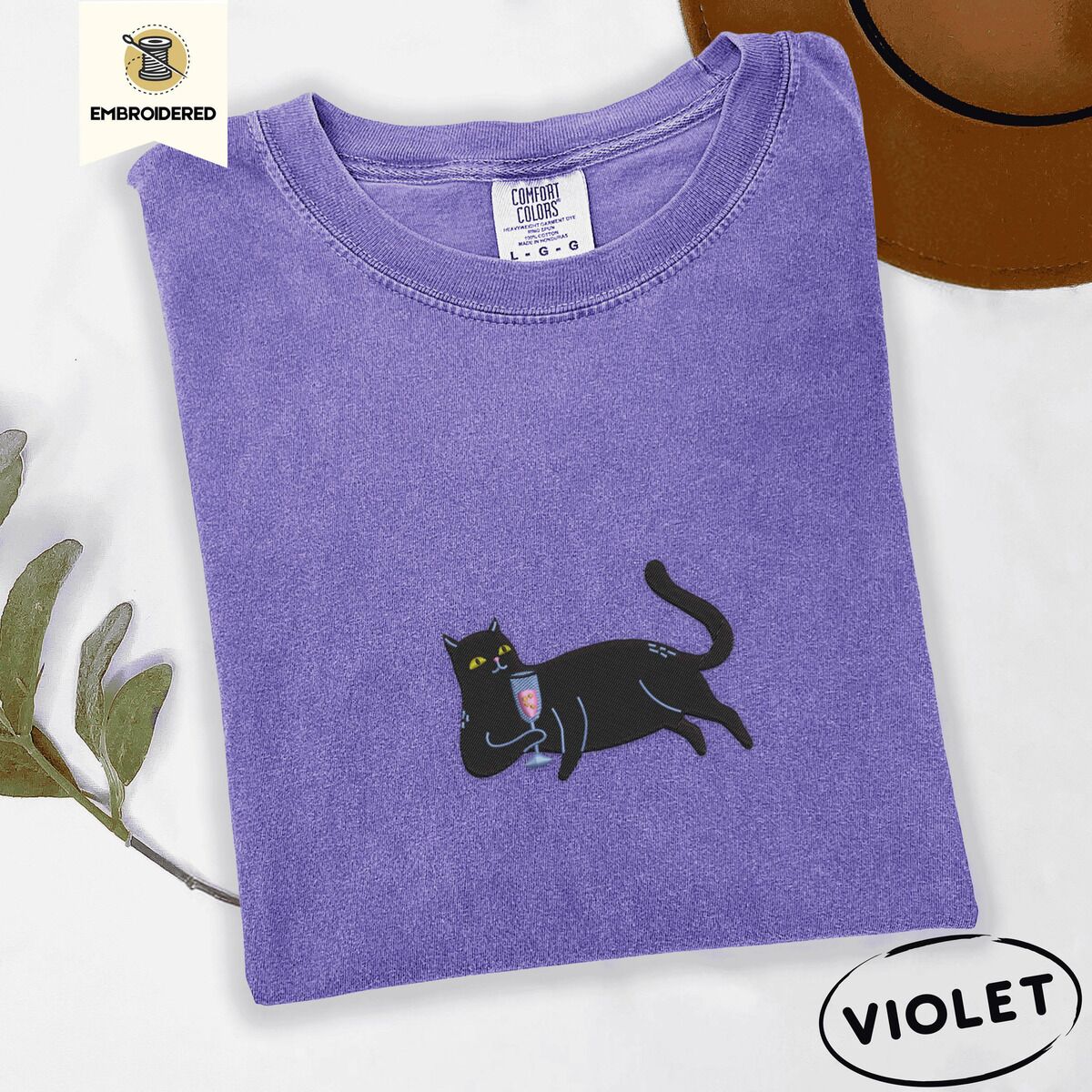 Black Cat Wine Shirt – Violet Violet Comfort Colors T-shirt embroidered with a black cat lounging on its side holding a stemmed glass of pink wine