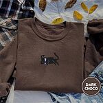 Dark Chocolate crewneck sweatshirt on a plaid flannel shirt with yellow autumn leaves and denim shorts, embroidered with a black cat lounging with a glass of pink wine in the center of the chest
