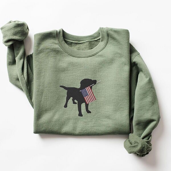 Military Green crewneck sweatshirt laid flat, a black Labrador holding a stars-and-stripes flag stitched across the chest