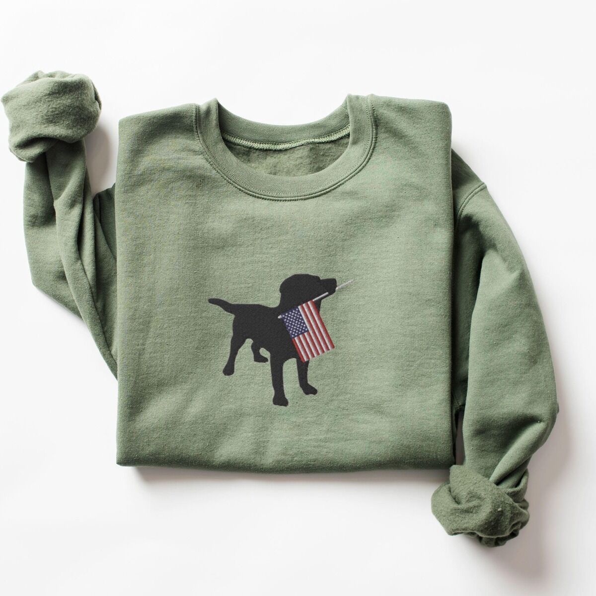 Black Lab American Flag Sweatshirt – Military Green Military Green crewneck sweatshirt laid flat, a black Labrador holding a stars-and-stripes flag stitched across the chest