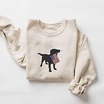 Sand crewneck sweatshirt laid flat with a rolled sleeve, embroidered with a black lab carrying a USA flag