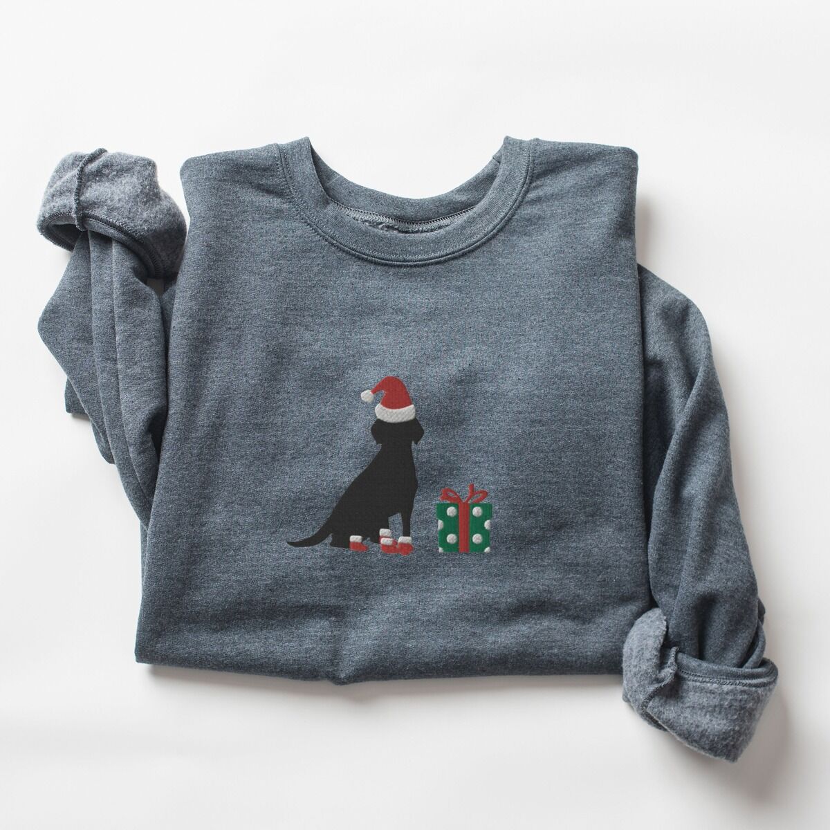 Black Lab Christmas Sweatshirt – Dark Heather Dark Heather crewneck sweatshirt laid flat with rolled sleeves, embroidered with a sitting black Labrador in a Santa hat and red booties beside a green gift box