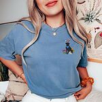 Woman wearing a Blue Jean T-shirt embroidered with a sitting black lab in bunny ears and a blue bandana with pink tulips, yellow flowers and a little bunny on the left chest