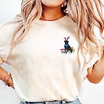Woman wearing a Ivory T-shirt embroidered with a sitting black lab in bunny ears and a blue bandana with pink tulips, yellow flowers and a little bunny on the left chest