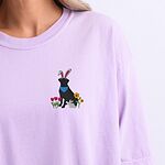 Woman wearing a Orchid T-shirt embroidered with a sitting black lab in bunny ears and a blue bandana with pink tulips, yellow flowers and a little bunny on the left chest