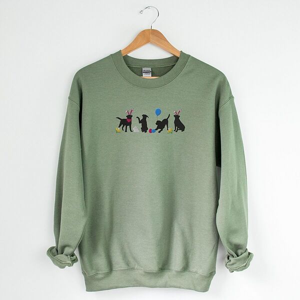 Military Green crewneck sweatshirt on a hanger, embroidered with four black lab silhouettes in bunny ears with a little bunny, Easter eggs, daffodils and a blue balloon
