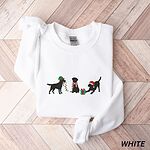 White crewneck sweatshirt laid flat on a chevron wood floor, embroidered with three black Labradors, one in an elf hat carrying Christmas lights, one in a candy-cane scarf and one in a Santa hat pawing a gift