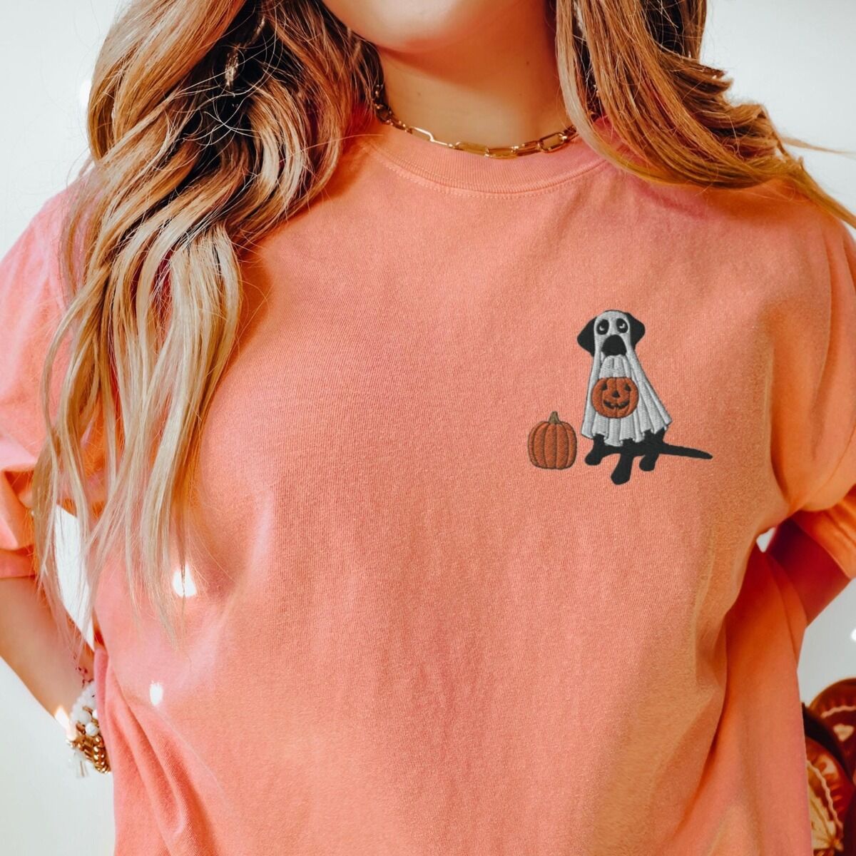 Black Lab Ghost Shirt – Terracotta Woman in a Terracotta T-shirt embroidered with a black lab trick-or-treating in a ghost sheet on the left chest