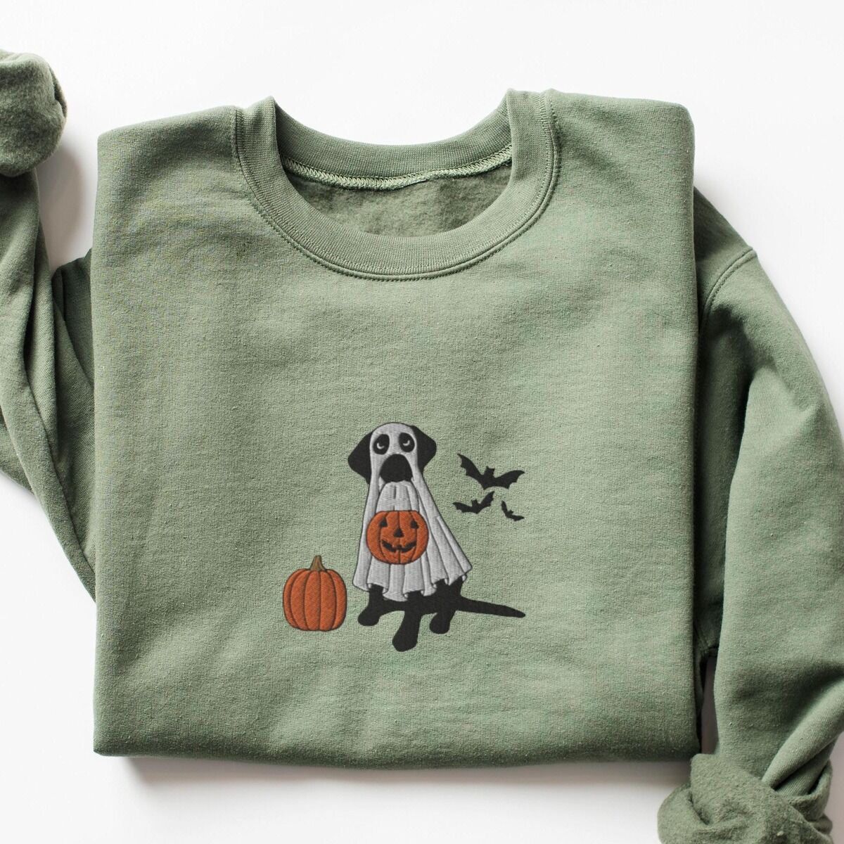 Black Lab Ghost Sweatshirt – Military Green Military Green crewneck sweatshirt laid flat, embroidered with a black lab in a ghost costume, an orange pumpkin and bats in the center of the chest