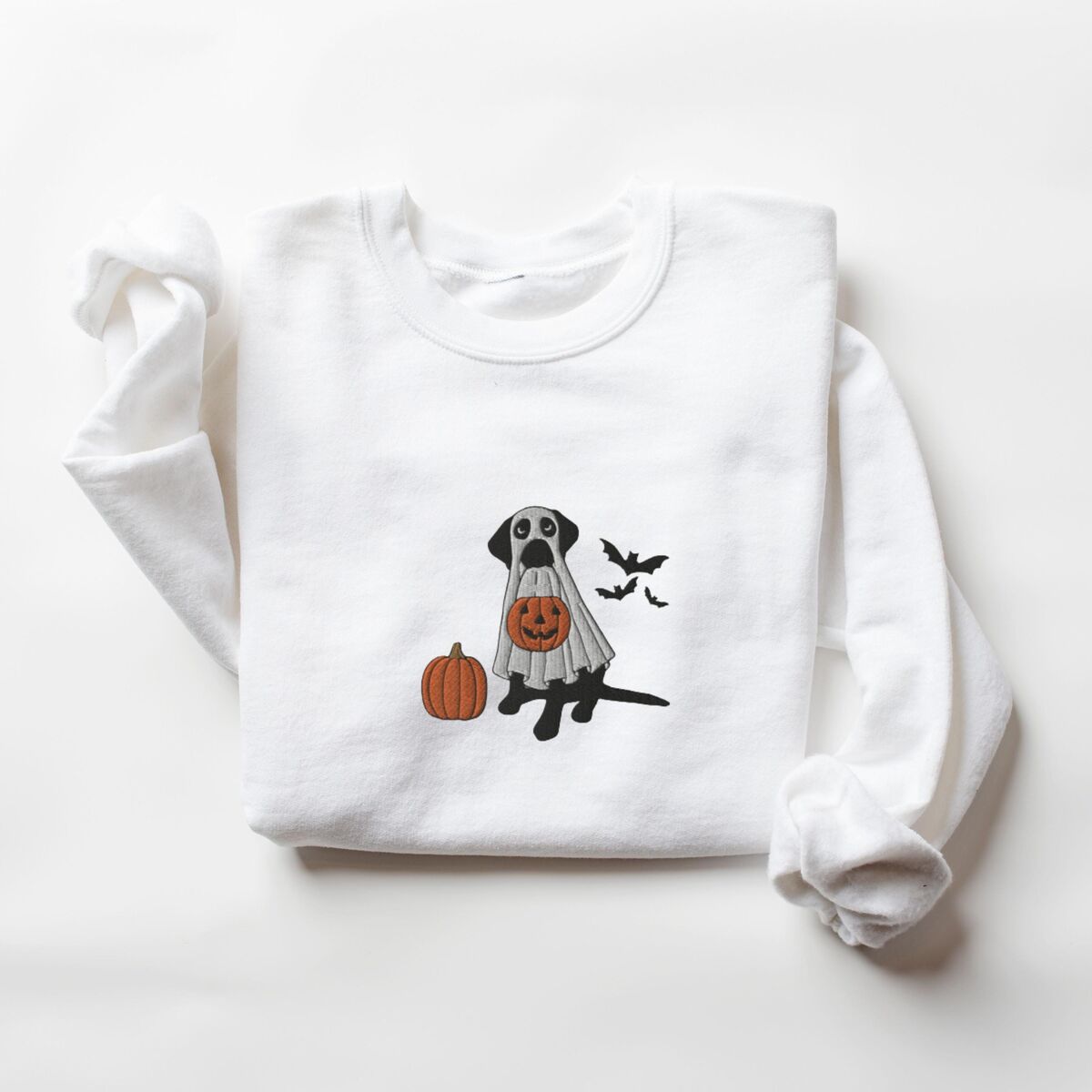 Black Lab Ghost Sweatshirt - White White crewneck sweatshirt laid flat, embroidered with a black Labrador under a ghost sheet with an orange pumpkin and three black bats