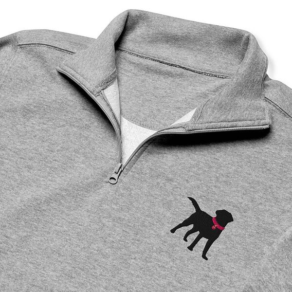 Close-up of the embroidered black lab on the chest of a grey quarter zip: a standing black Labrador with its tail up, head turned back and a hot pink collar and tag