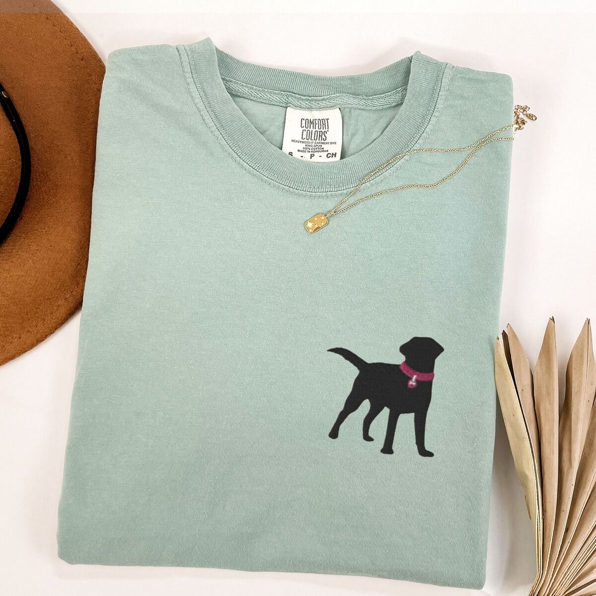 Black Lab Silhouette Shirt – Bay Bay T-shirt laid flat with a necklace, embroidered with a small black Labrador silhouette in a hot pink collar and tag on the left chest