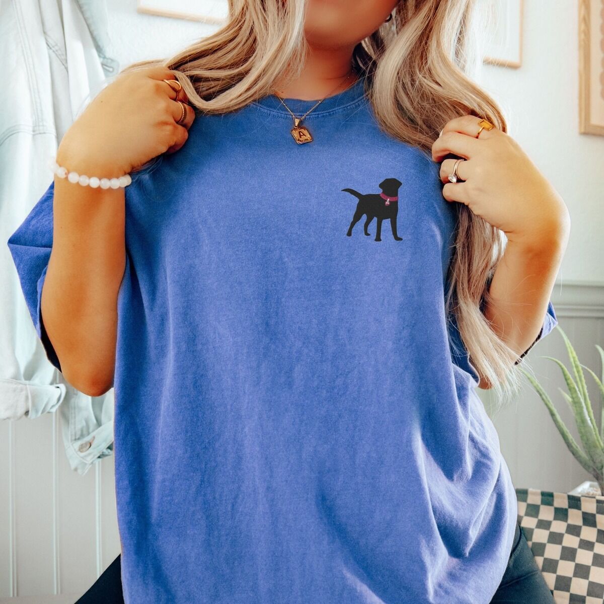 Black Lab Silhouette Shirt – Flo Blue Woman in a Flo Blue T-shirt embroidered with a small black Labrador silhouette in a hot pink collar on the left chest