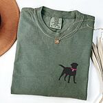 Moss T-shirt laid flat with a necklace, embroidered with a small black Labrador silhouette in a hot pink collar and tag on the left chest