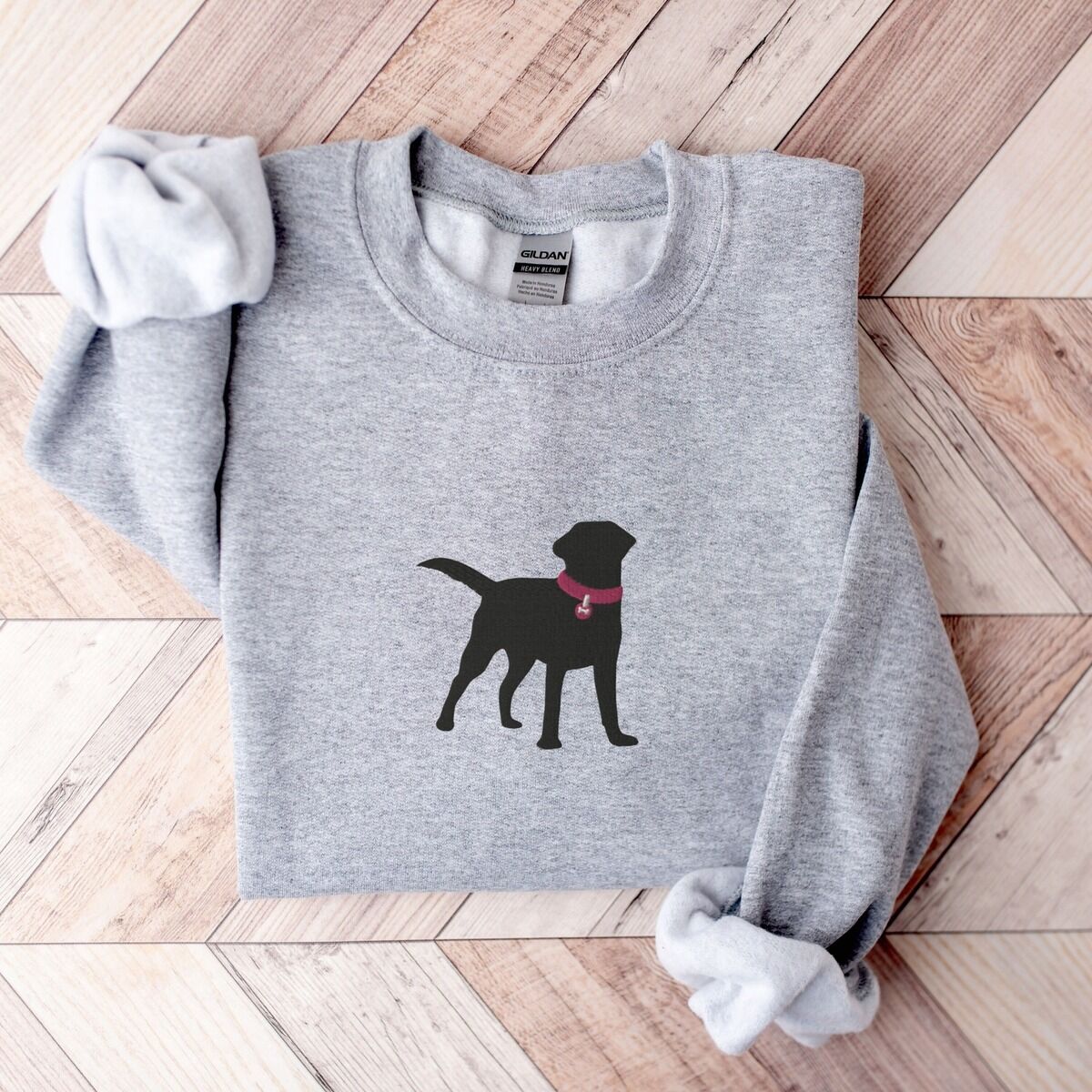 Black Lab Silhouette Sweatshirt - center chest Sport Grey Sport Grey crewneck sweatshirt on herringbone wood with a larger black Labrador silhouette in a hot pink collar centered on the chest