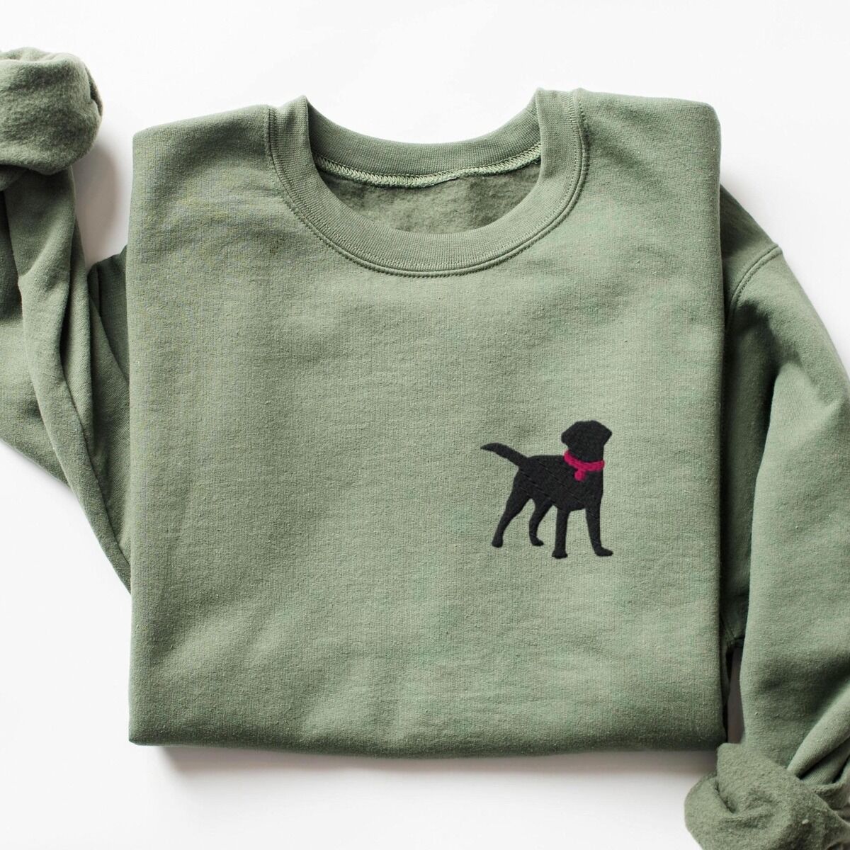 Black Lab Silhouette Sweatshirt – Military Green Military Green crewneck sweatshirt laid flat on white, embroidered with a small black Labrador silhouette in a hot pink collar and tag on the left chest