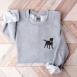 Sport Grey crewneck sweatshirt laid flat on herringbone wood, embroidered with a small black Labrador silhouette in a yellow collar