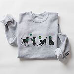 Sport Grey crewneck sweatshirt laid flat, embroidered with four black lab silhouettes in green bandanas with a shamrock, a clover balloon and a leprechaun hat
