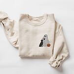 Sand crewneck sweatshirt laid flat on a white background, embroidered with a small ghost lab mom sipping red wine with a black lab sitting against her and a jack-o'-lantern, on the left chest