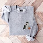 Sport Grey crewneck sweatshirt laid flat on a wood floor, embroidered with a small ghost lab mom sipping red wine with a black lab sitting against her and a jack-o'-lantern, on the left chest