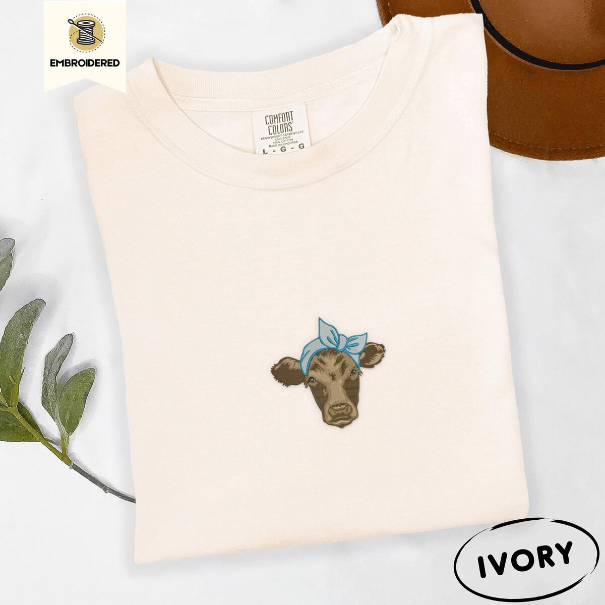 Brown Cow Shirt – Ivory Ivory Comfort Colors T-shirt embroidered with a brown calf head wearing a light blue bandana tied in a bow