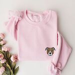 Light Pink crewneck sweatshirt laid flat with pink roses, embroidered with a small minimalist fawn and white pit bull face with grey ears on the left chest