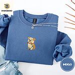 Indigo Blue crewneck sweatshirt folded with light jeans and dried twigs, embroidered with a fawn and cream English bulldog puppy in a red collar chewing a string of Christmas lights