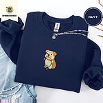 Navy crewneck sweatshirt folded with ripped jeans and a silver chain necklace, embroidered with a fawn and cream English bulldog puppy in a red collar chewing a string of Christmas lights
