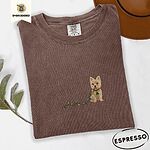 Espresso Comfort Colors T-shirt embroidered with a wheaten Cairn terrier puppy in a red collar chewing the plug of a string of Christmas lights