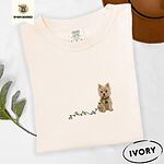 Ivory Comfort Colors T-shirt embroidered with a wheaten Cairn terrier puppy in a red collar chewing the plug of a string of Christmas lights