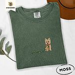 Moss Comfort Colors T-shirt embroidered with a wheaten Cairn terrier puppy in a red collar chewing the plug of a string of Christmas lights