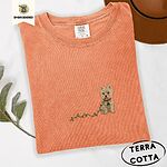 Terracotta Comfort Colors T-shirt embroidered with a wheaten Cairn terrier puppy in a red collar chewing the plug of a string of Christmas lights