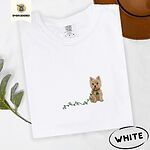 White Comfort Colors T-shirt embroidered with a wheaten Cairn terrier puppy in a red collar chewing the plug of a string of Christmas lights