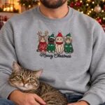 Cat dad wearing the Meowy Christmas sweatshirt with his tabby cat next to a Christmas tree