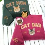Matching CAT MOM and CAT DAD sweatshirts in forest green and maroon with embroidered orange and tabby cat portraits and sleeve names
