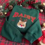 Cat name Christmas sweatshirt in Forest Green with a reindeer cat portrait, laid out as a Christmas gift